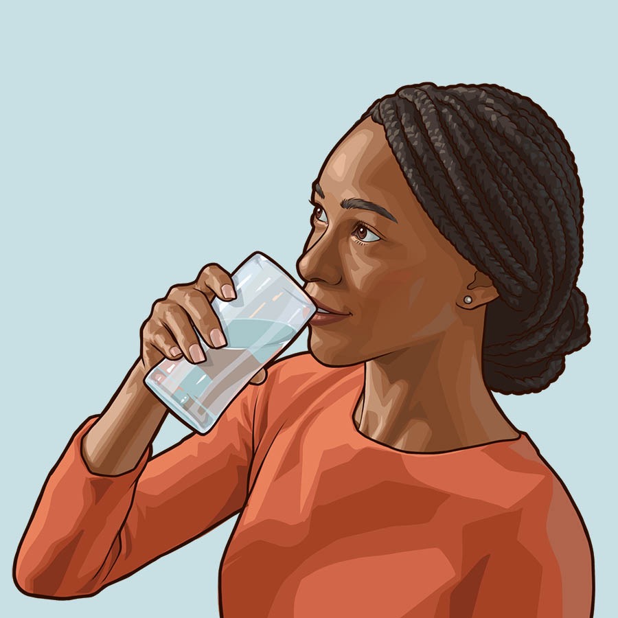 Una donna beve un bicchiere d’acqua.