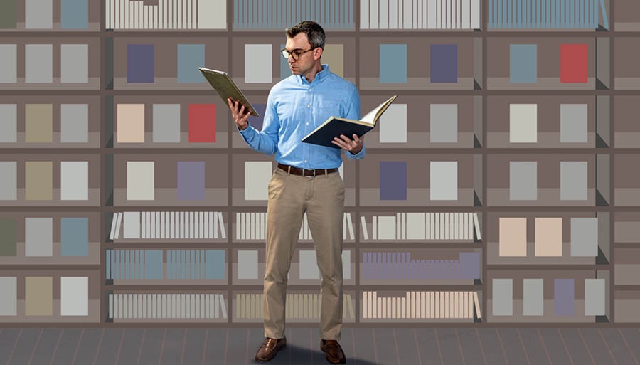 Un uomo guarda un libro che ha scelto e lo confronta con le ricerche che ha fatto sul suo dispositivo elettronico