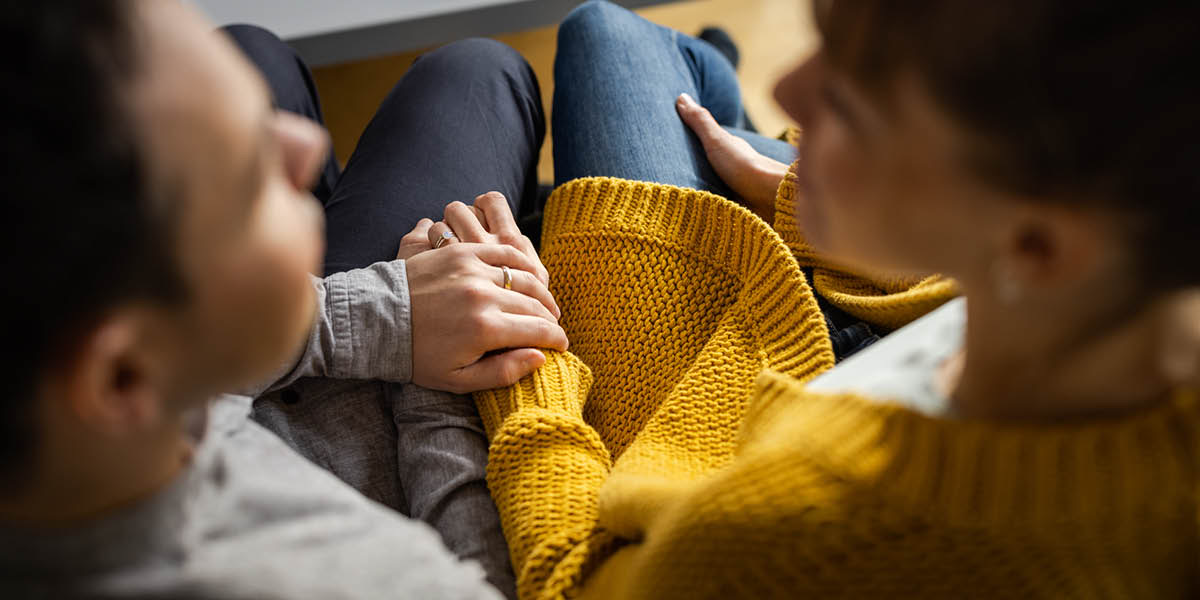 夫婦が並んで座っている。互いの手を握って話している。