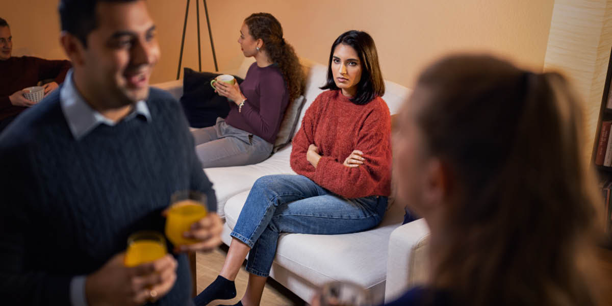社交的な場で女性と話している夫を見て，妻が不機嫌そうにしている。