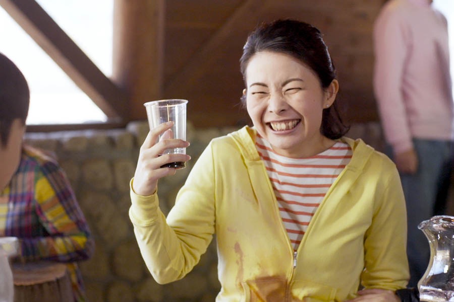 男の子がぶつかったせいで服に飲み物がこぼれたが，美樹は笑っている。