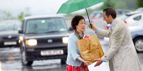 男性が，紙袋を抱えた女性を助けている