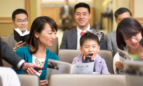 集会で男の子が注解するのを，姉妹が助けている