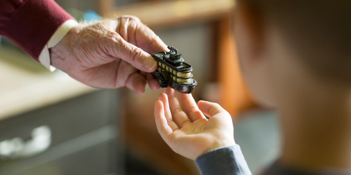 老人が幼い少年に船の形をした鉛筆削りを手渡している