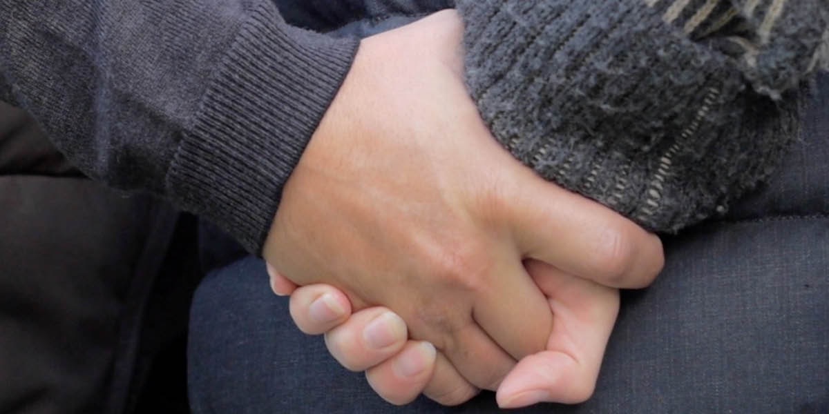 1人の男性と1人の女性が手をつないでいる。