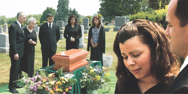 Grieving people around a small casket in a graveyard
