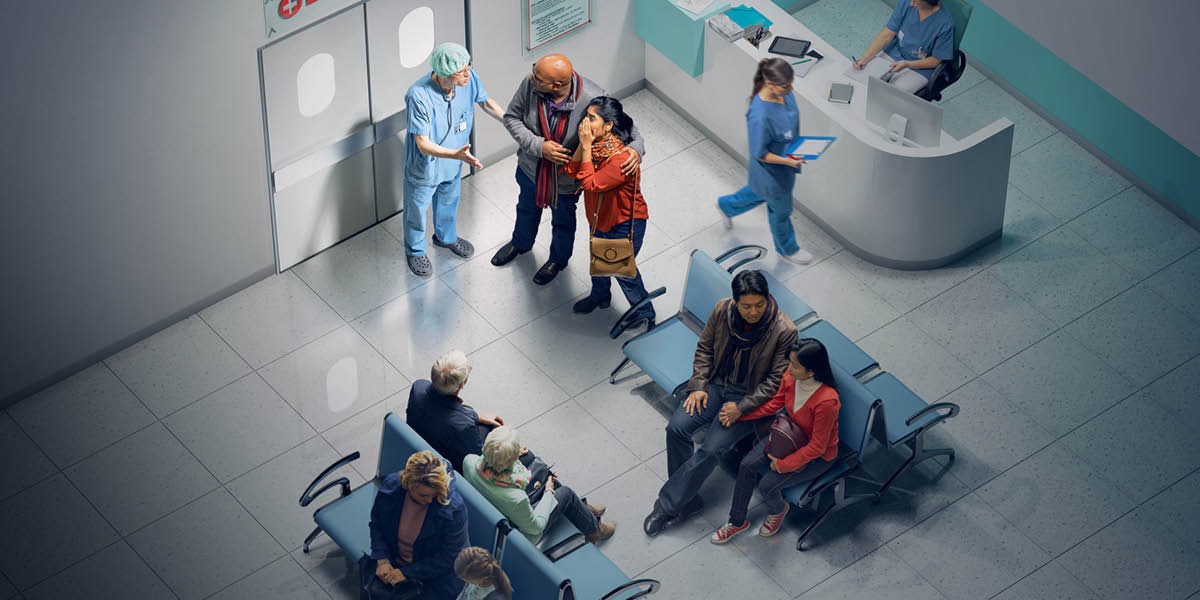 Un sala di ospital. Un dotor sta ta da un notísia kasábi pa un kazal ki sta sakédu pértu di pórta di entrada. Otus algen sta ta spéra pa es djobedu.