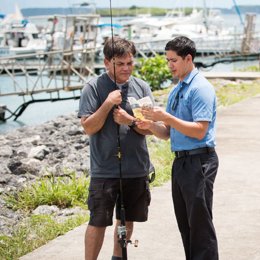 Um irmão usa um folheto para pregar a um pescador numa marina