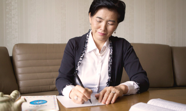 An older woman writing a letter