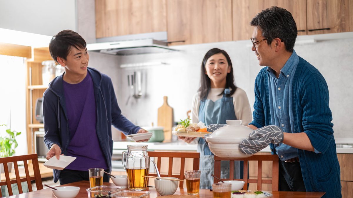 한 청소년 형제가 가족과 식사하기 전에 부모님을 도와 식탁을 차리고 있습니다.