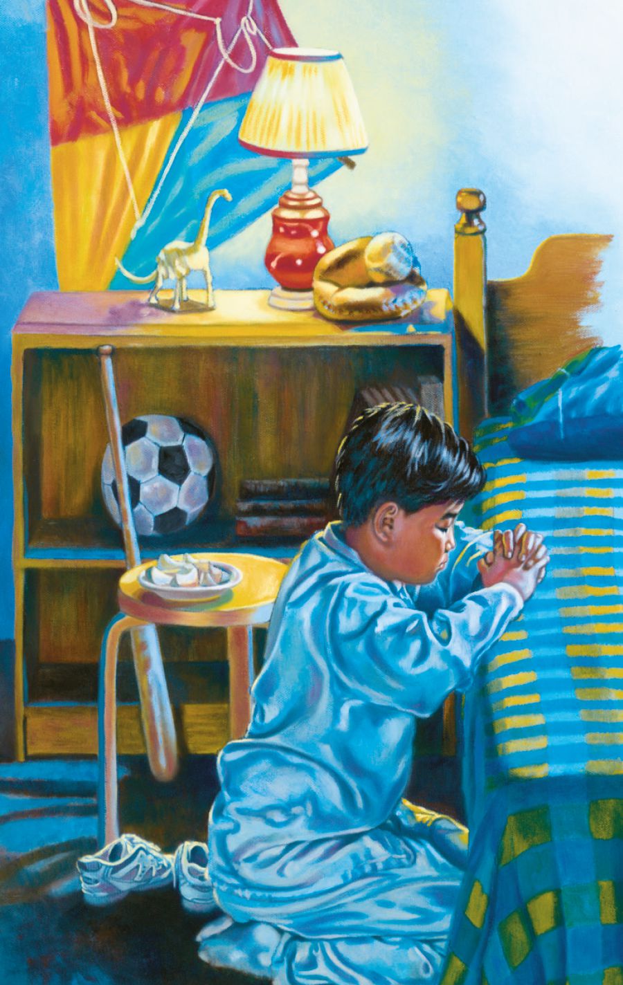 A boy kneels beside his bed and prays