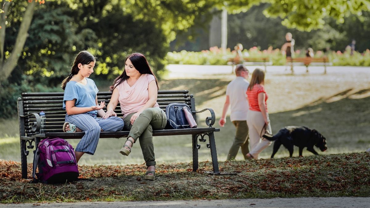 The young girl and her ma sitting down on the bench in one fine place and she telling her ma what in her heart.