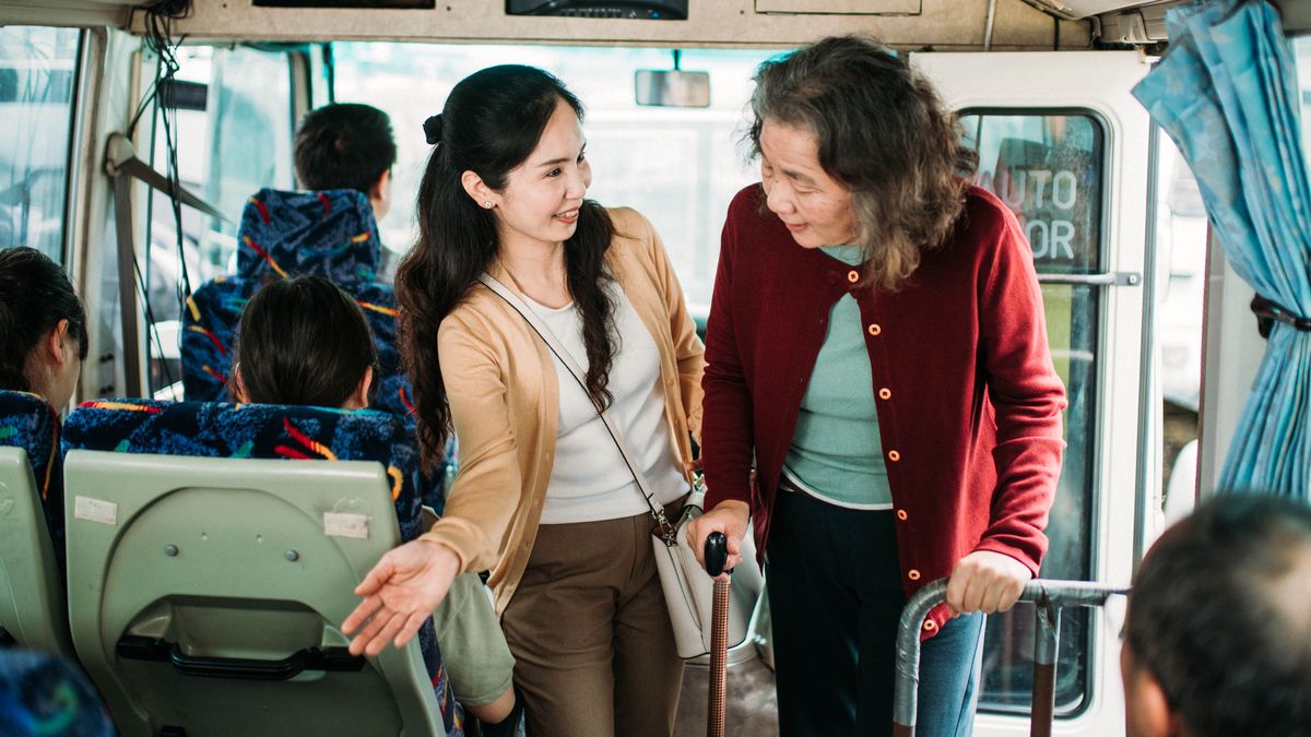 En un autobús, una hermana le cede el asiento a una señora mayor.