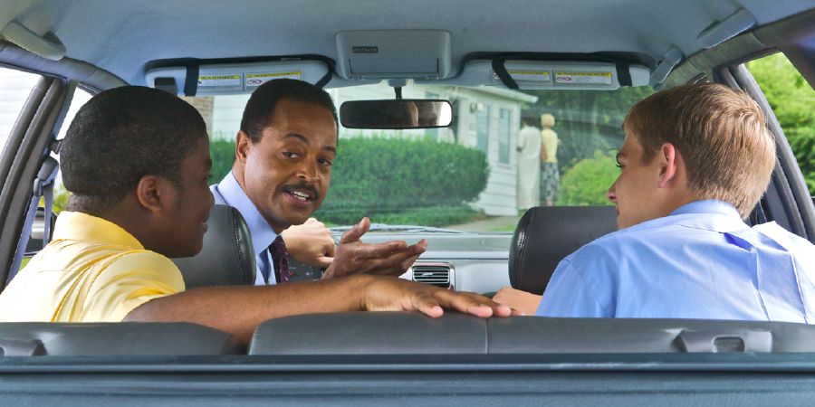 Un hermano maduro hablando con dos jóvenes en un auto.