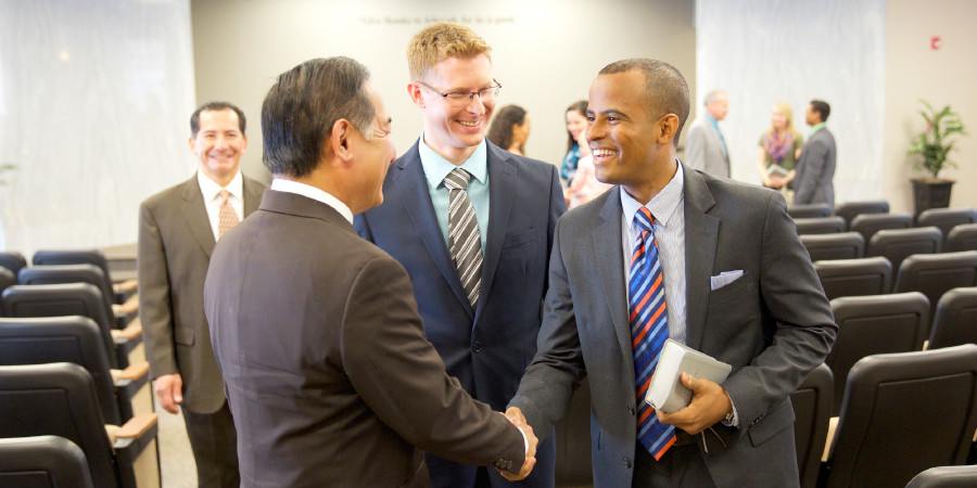 Jehovah’s Witnesses of various races greet one another in a Kingdom Hall