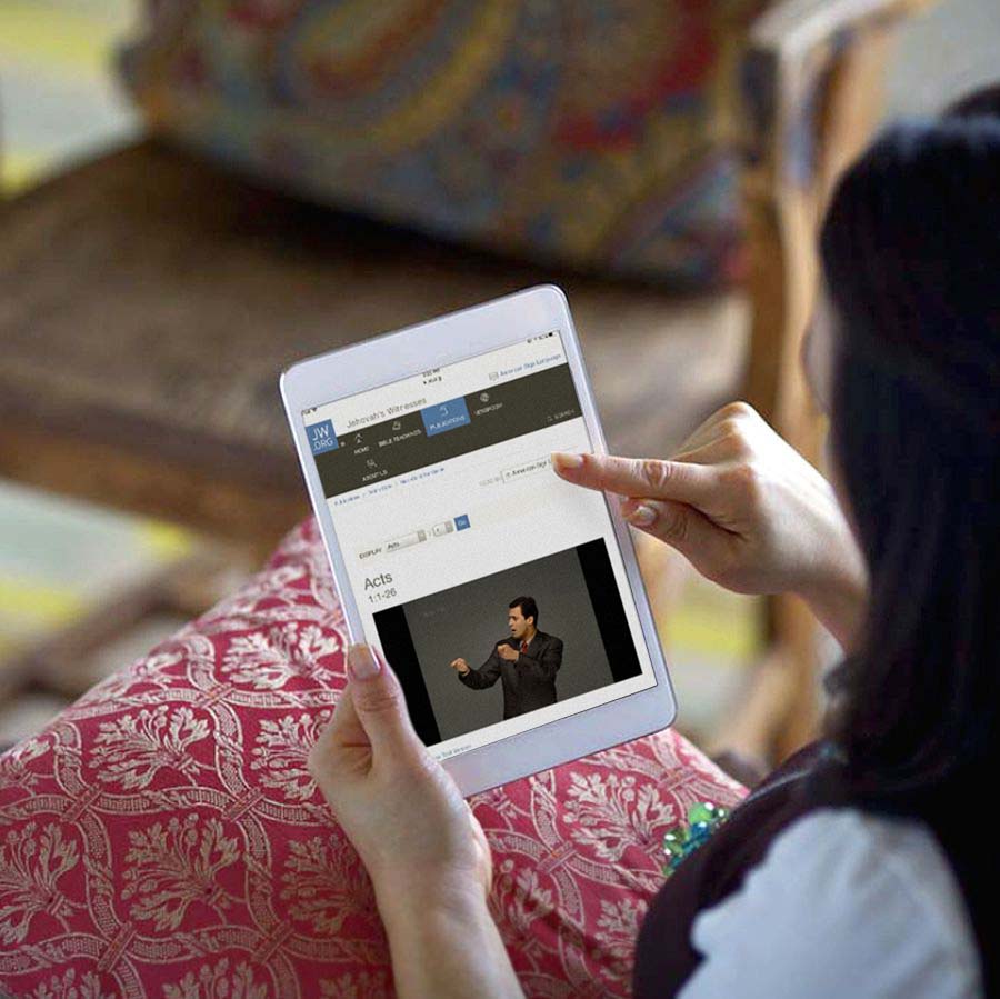 Una mujer usando su tableta para leer la Biblia en línea en jw.org.