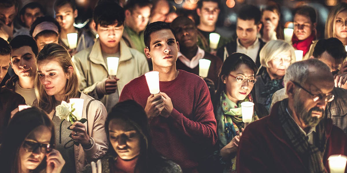Unas personas sujetando velas en señal de duelo