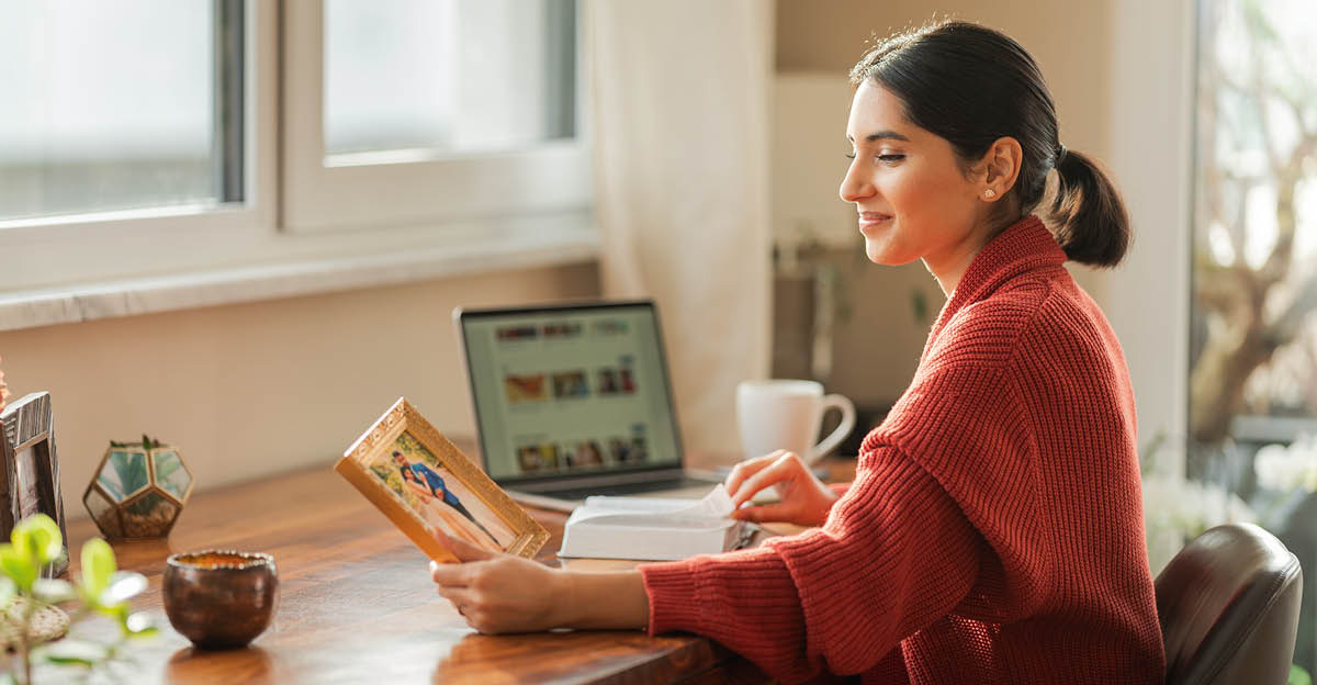 Истата сопруга се чувствува радосно додека гледа една фотографија од својата венчавка. Пред неа има отворена Библија.