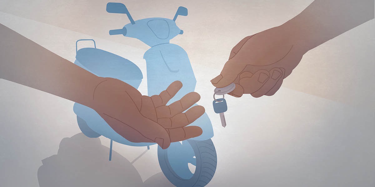 Penjual motosikal menyerahkan kunci kepada pembeli. Motosikal ada di belakang mereka.