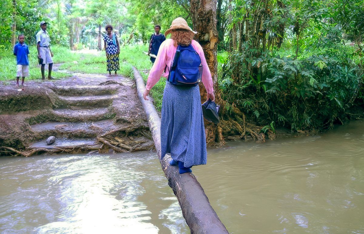 Leann meniti batang kayu untuk menyeberangi sungai.