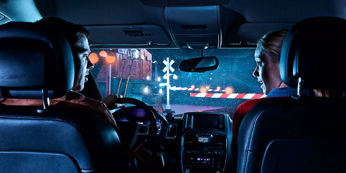 Sepasang suami isteri berada di dalam kereta di hadapan tanda isyarat landasan kereta api