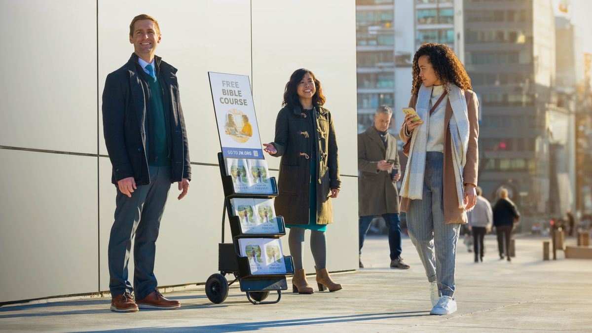 Koppja qegħdin bit-trolly li fuq il-poster hemm miktub “Kors tal-​Bibbja b’Xejn” u mara għaddejja u qed tħares lejn it-trolley.