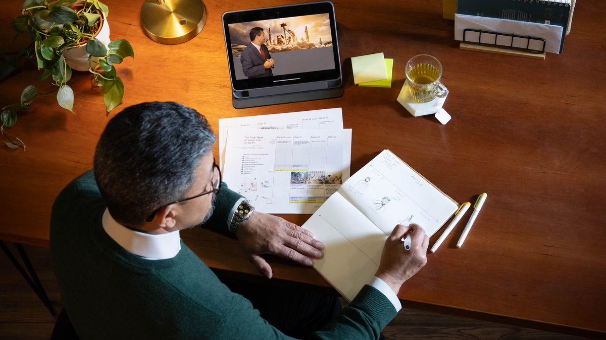 Um irmão mais velho a usar um ‘tablet’, uma Bíblia e um caderno para fazer o seu estudo pessoal. Ele está a consultar a tabela “A Última Semana de Jesus na Terra (Parte 2)” no Apêndice B12-B da “Tradução do Novo Mundo” e o capítulo 129 do livro “Jesus — O Caminho, a Verdade e a Vida”.
