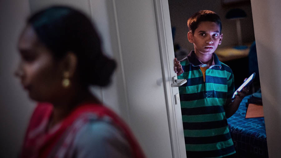 एक ठिटा आमा आफ्नो कोठा भएतिरबाट जाँदै गरेकी चाल पाएर एउटा हातमा मोबाइल समात्दै बिस्तारै कोठाको ढोका लगाउन खोज्दै छ।