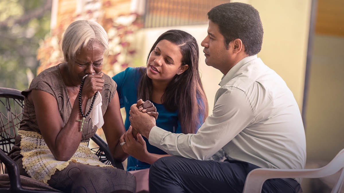 प्रियजन गुमाएकोले शोक मनाइरहेको आफ्नो आफन्तलाई एक साक्षी दम्पति सान्त्वना दिन्छन्‌
