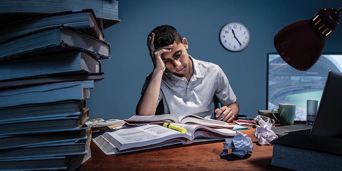 Een jongen die ’s avonds laat zijn huiswerk maakt terwijl de tv aanstaat.