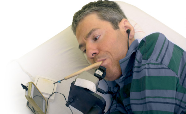 Félix Alarcón die een stokje in zijn mond houdt en daarmee zijn telefoon bedient