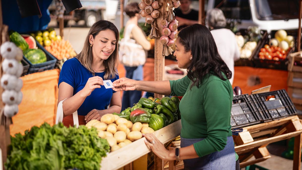 De zuster geeft een marktkramer een contactkaartje van jw.org.