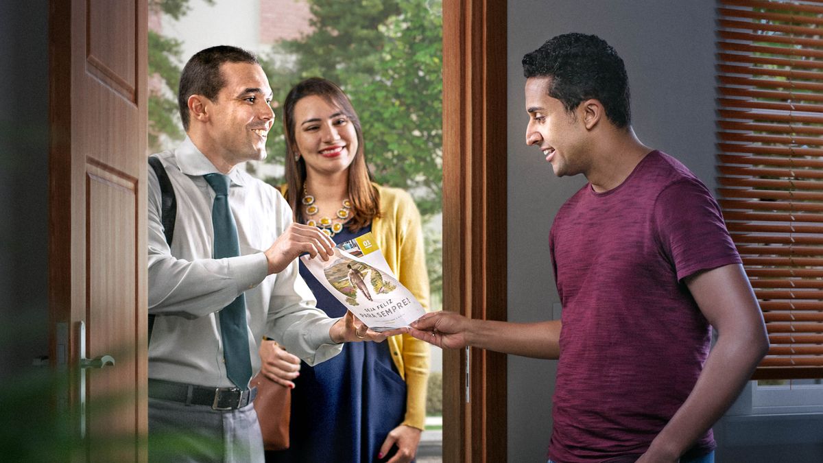 A couple in the door-to-door ministry, offering a man the brochure “Enjoy Life Forever!”