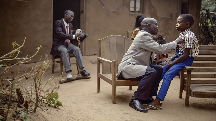 Bzinthu bzomwe bzikucitika mu vidiyo ya msolo wakuti ‘Lufoyi Lanu Lireke Kumala . . . Penu Munkugumana na Bvuto la Kobiri—ku Kongo.’ M’bale akubvazika mwana kuti ayende ku mtsonkhano wacigawo.