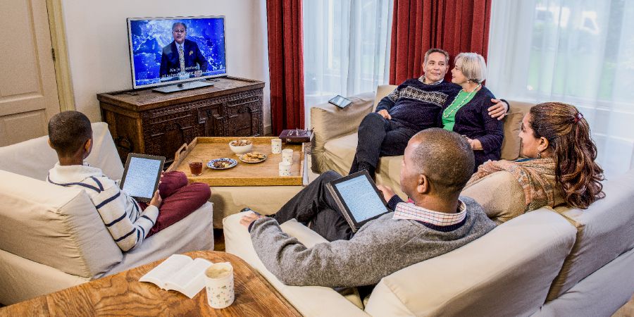 Un pareha di edat ta wak JW Broadcasting ku un famia mas yòn
