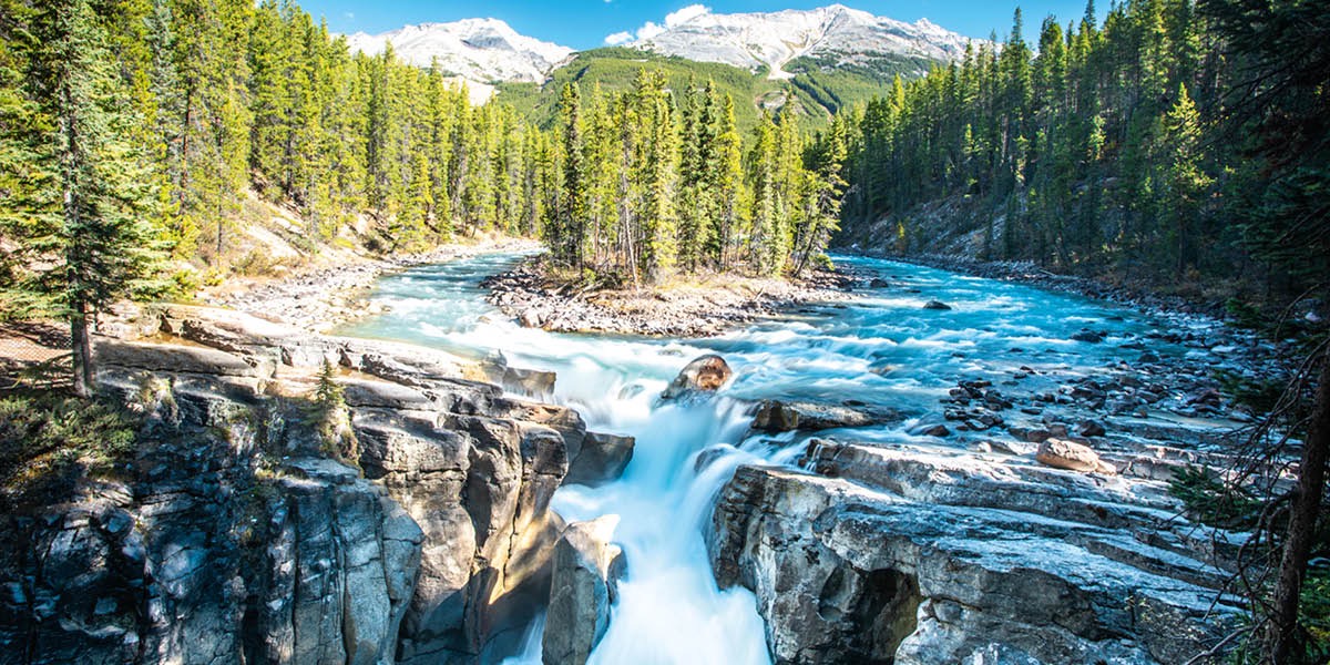Un riu ta kore den direkshon di un waterval. E riu ta rondoná pa un mondi i seru haltu tapá ku sneu.