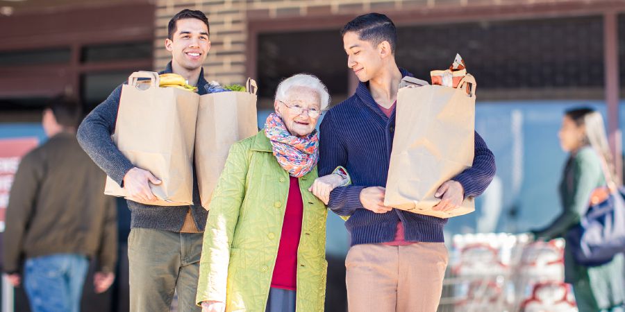 Two young brothers dey help one old sister carry im load