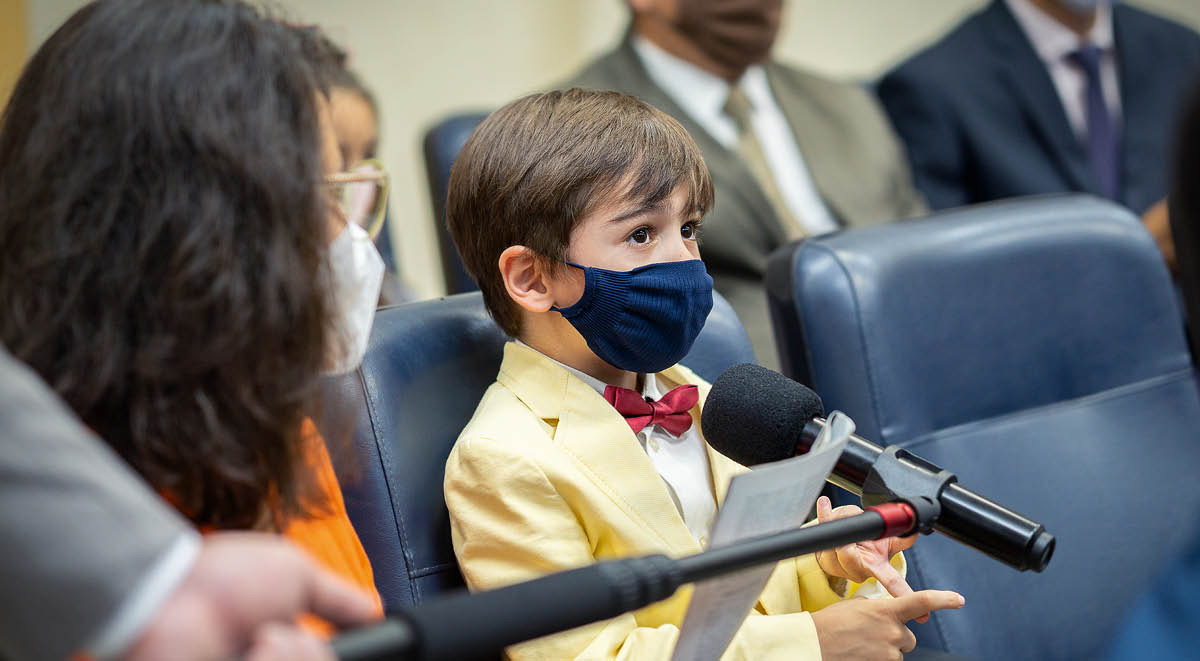 Brata iusim boom microphone for smol boy koment lo kongregeson meeting. Smol boy and olketa narawan wea attendim meeting werem mask.