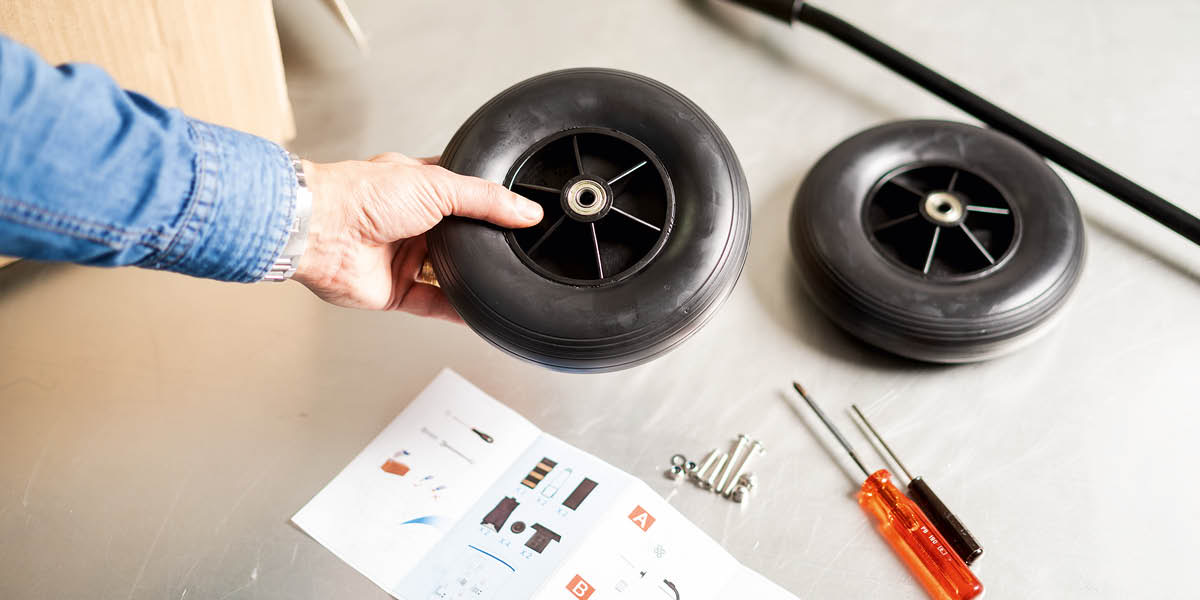 Instrukcje, narzędzia i części zamienne do wózka z publikacjami — kółka, oś, śruby i nakrętki.