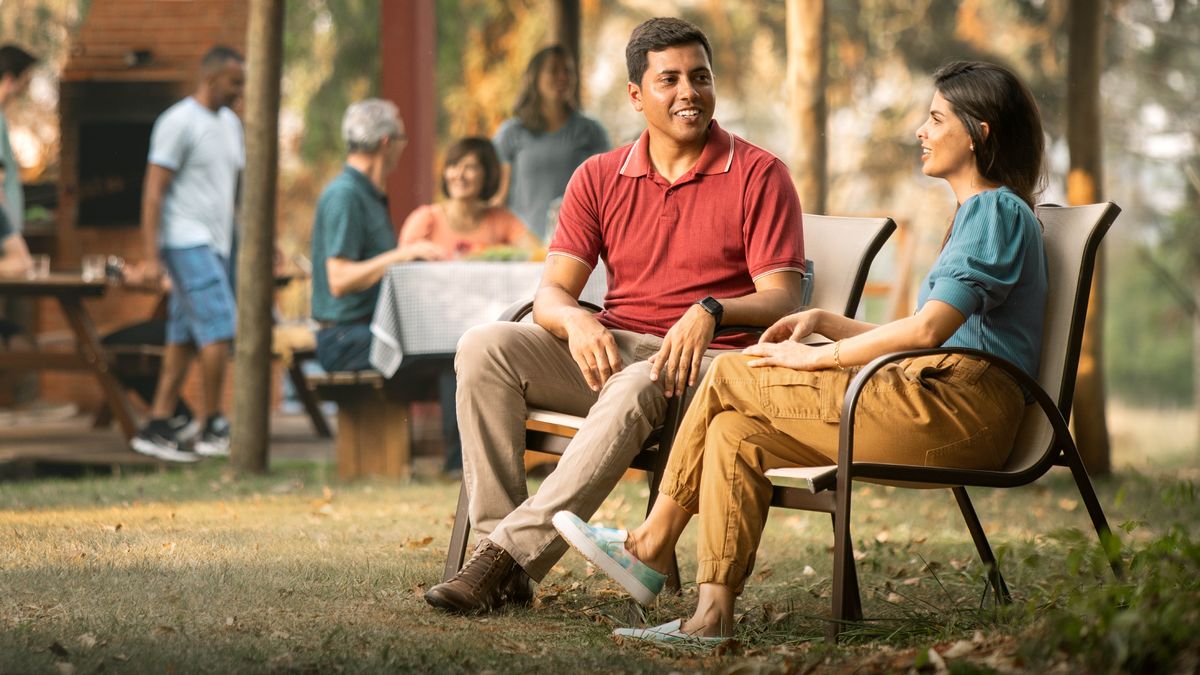 Um casal que está a namorar sentados juntos durante um convívio. Eles conversam em privado enquanto outros irmãos estão a conviver.