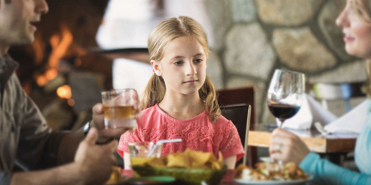 Uma menina presta atenção quando os pais bebem bebidas alcoólicas