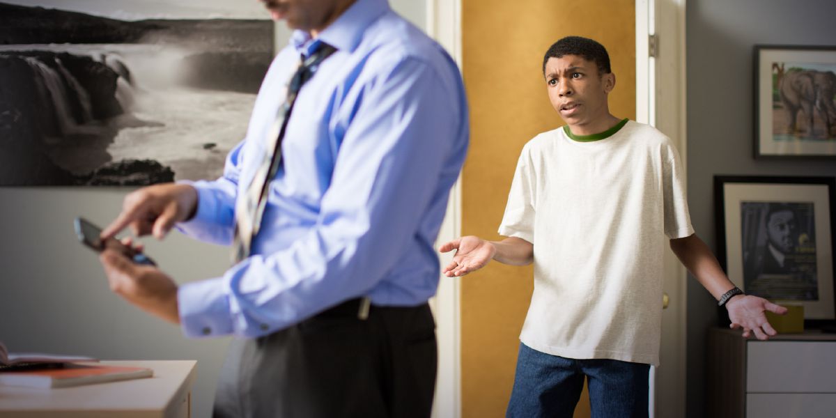 Um pai a olhar para o telemóvel do filho, e o filho irritado