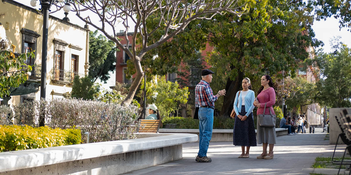 Um homem conversa com duas irmãs num jardim.