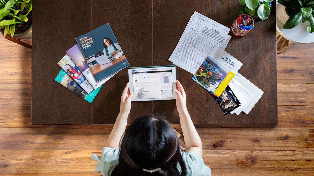 Uma irmã jovem usa o “tablet” para pesquisar alvos. Do seu lado esquerdo, estão brochuras sobre educação secular. Do lado direito, ela tem uma petição para expandir o seu serviço teocrático e informação sobre Betel.