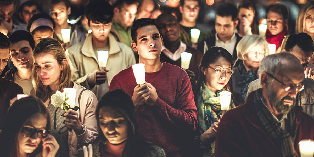 Pessoas enlutadas seguram velas