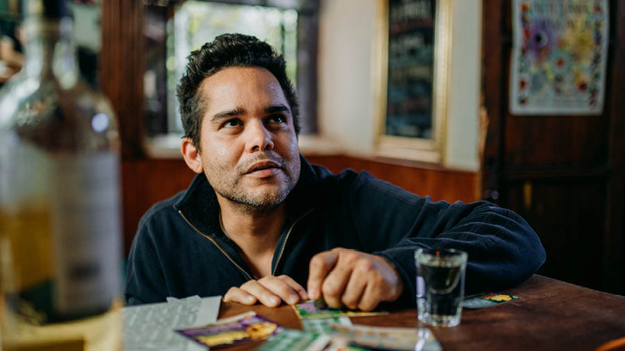 Um homem olha para cima enquanto raspa um bilhete da lotaria.