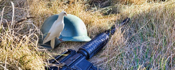 Uma pomba, um capacete militar, uma arma de guerra