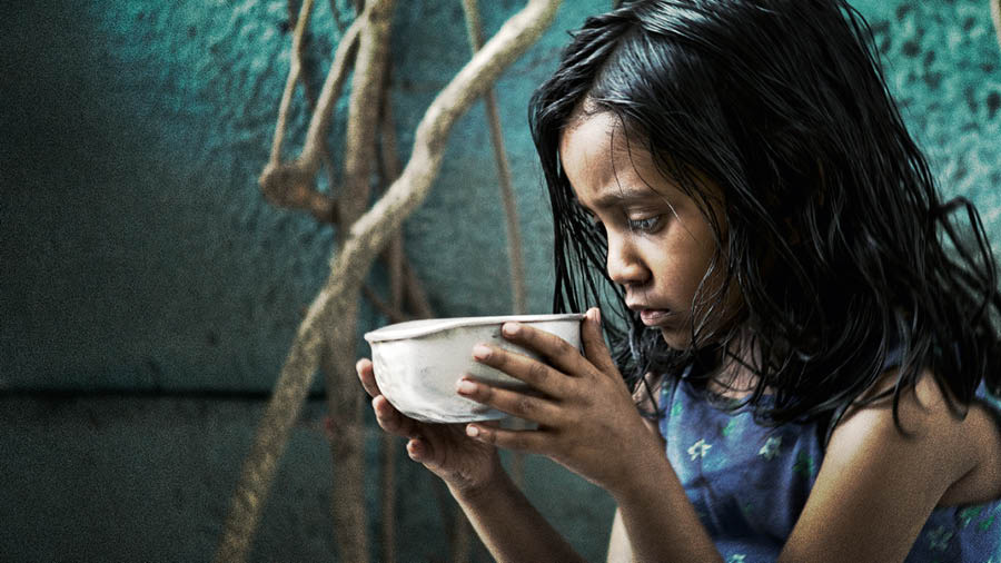 Uma menina com fome segurando uma tigela.