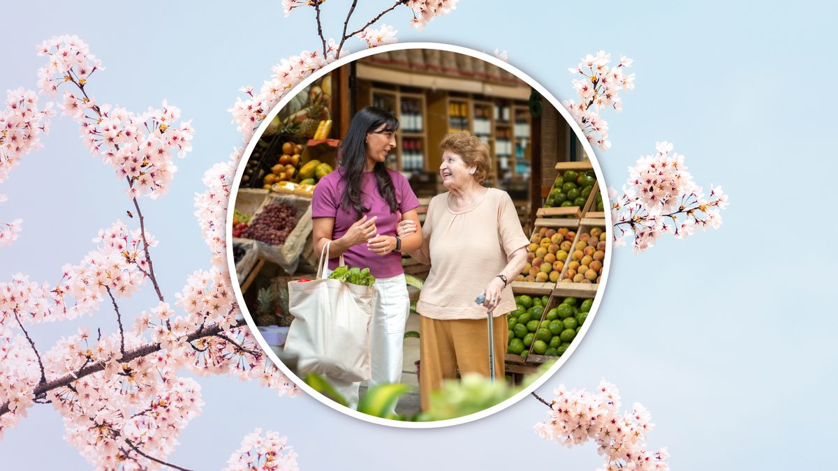 An elderly sister holding on to the arm of a young sister as they grocery shop together.