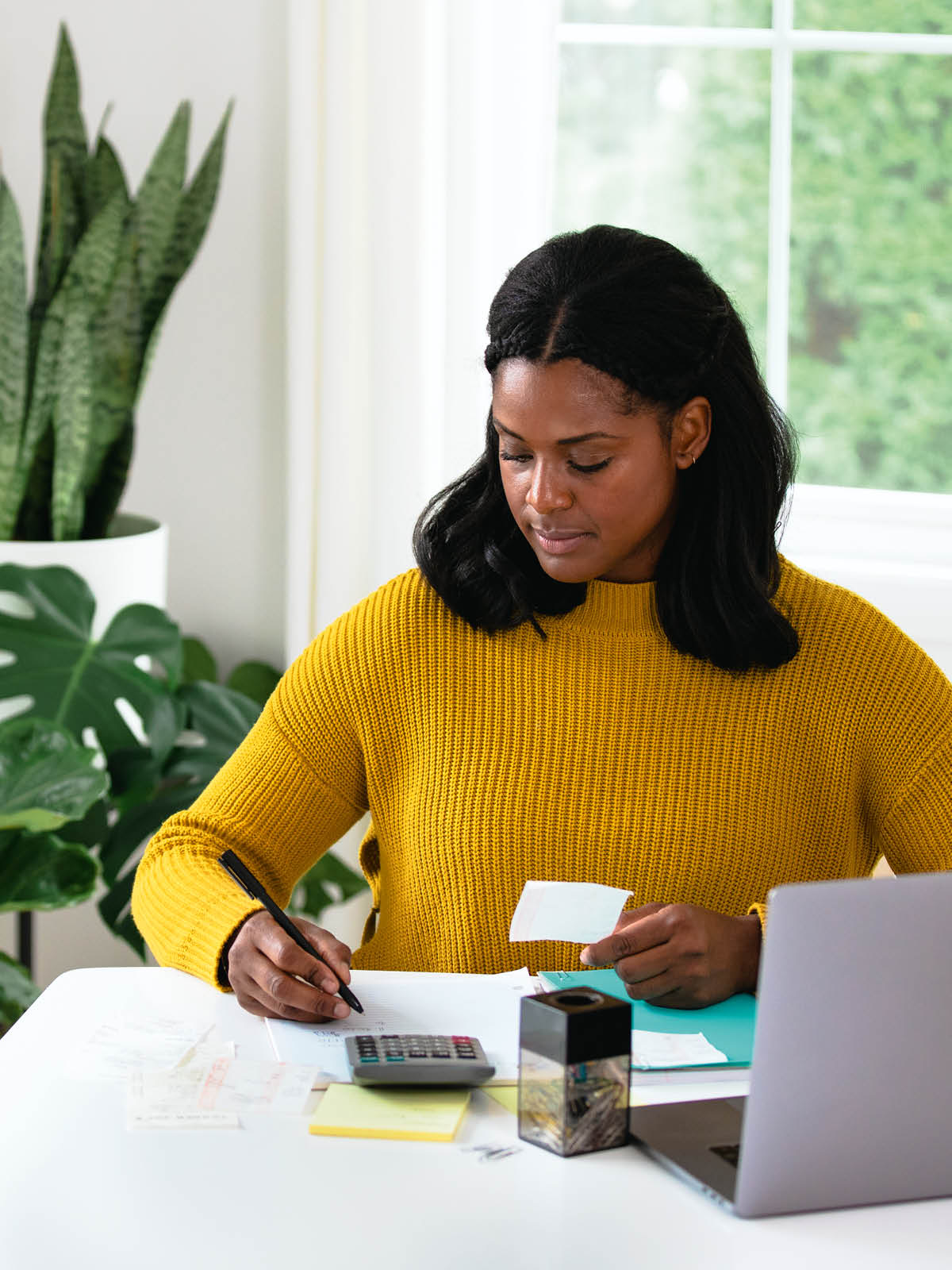 Uma mulher usando uma calculadora e registrando as informações de um recibo.